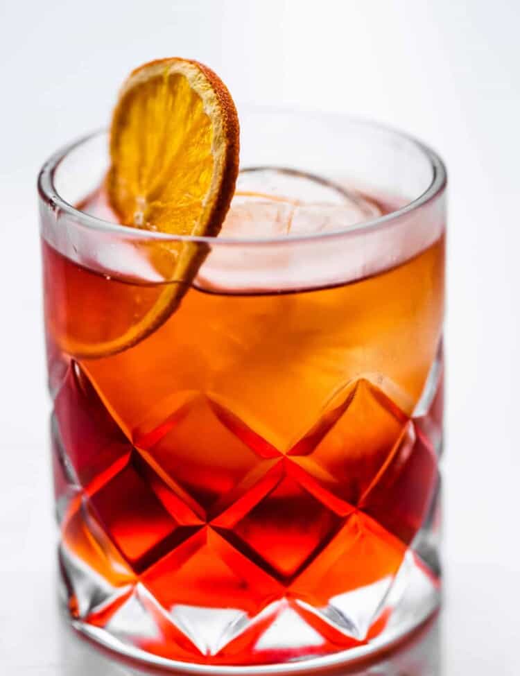 a mezcal negroni in a rocks glass with a dehydrated orange wheel.