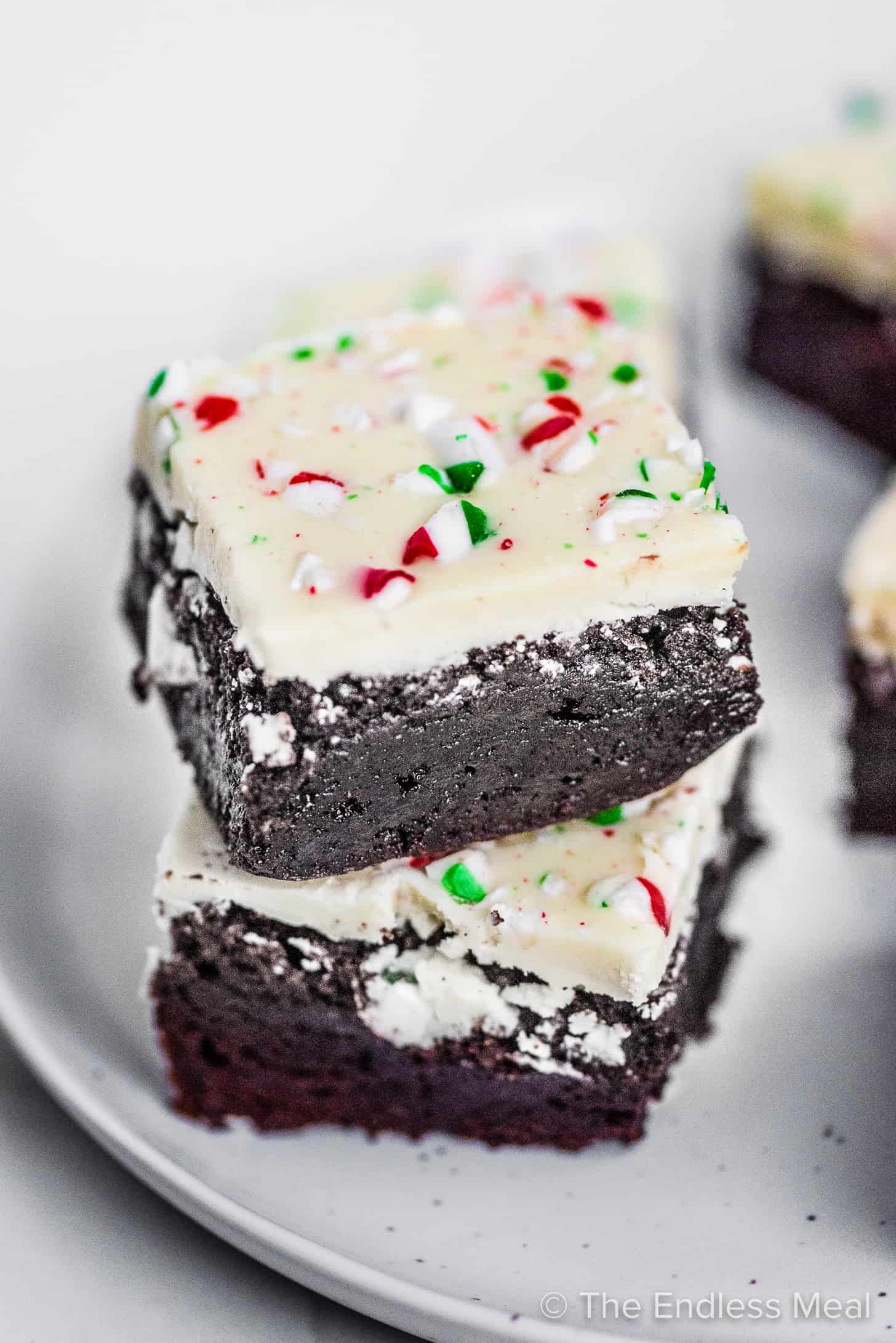 A stack of 2 christmas candy cane brownies on a plate. 