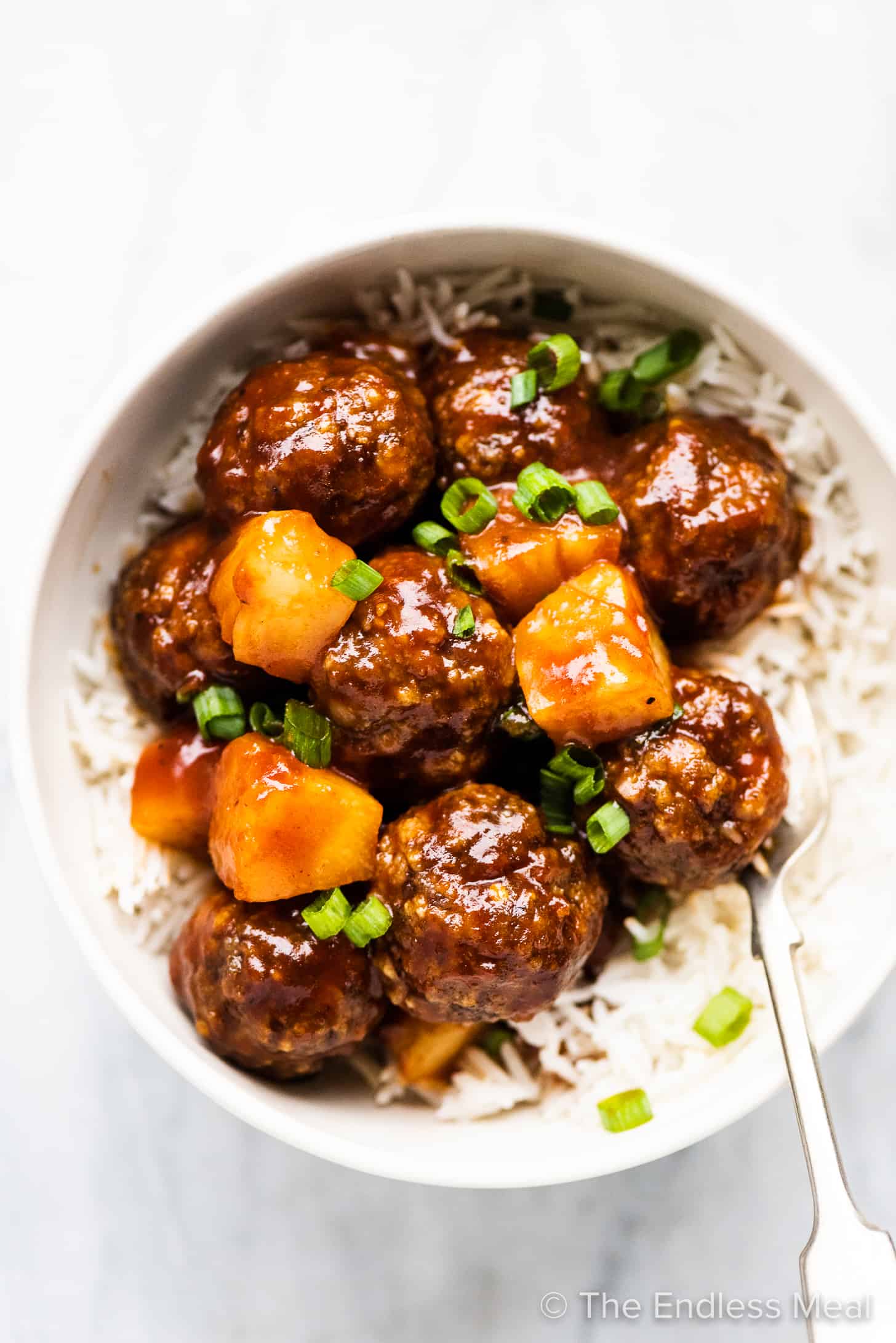 Pineapple Meatballs in a white bowl with rice.
