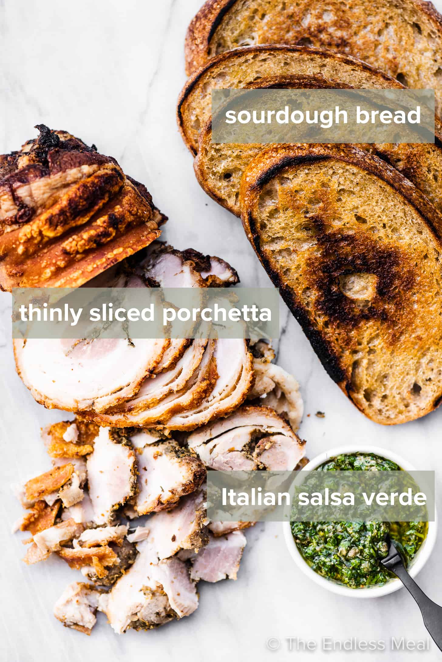 The ingredients needed to make a porchetta sandwich laid out on a countertop.