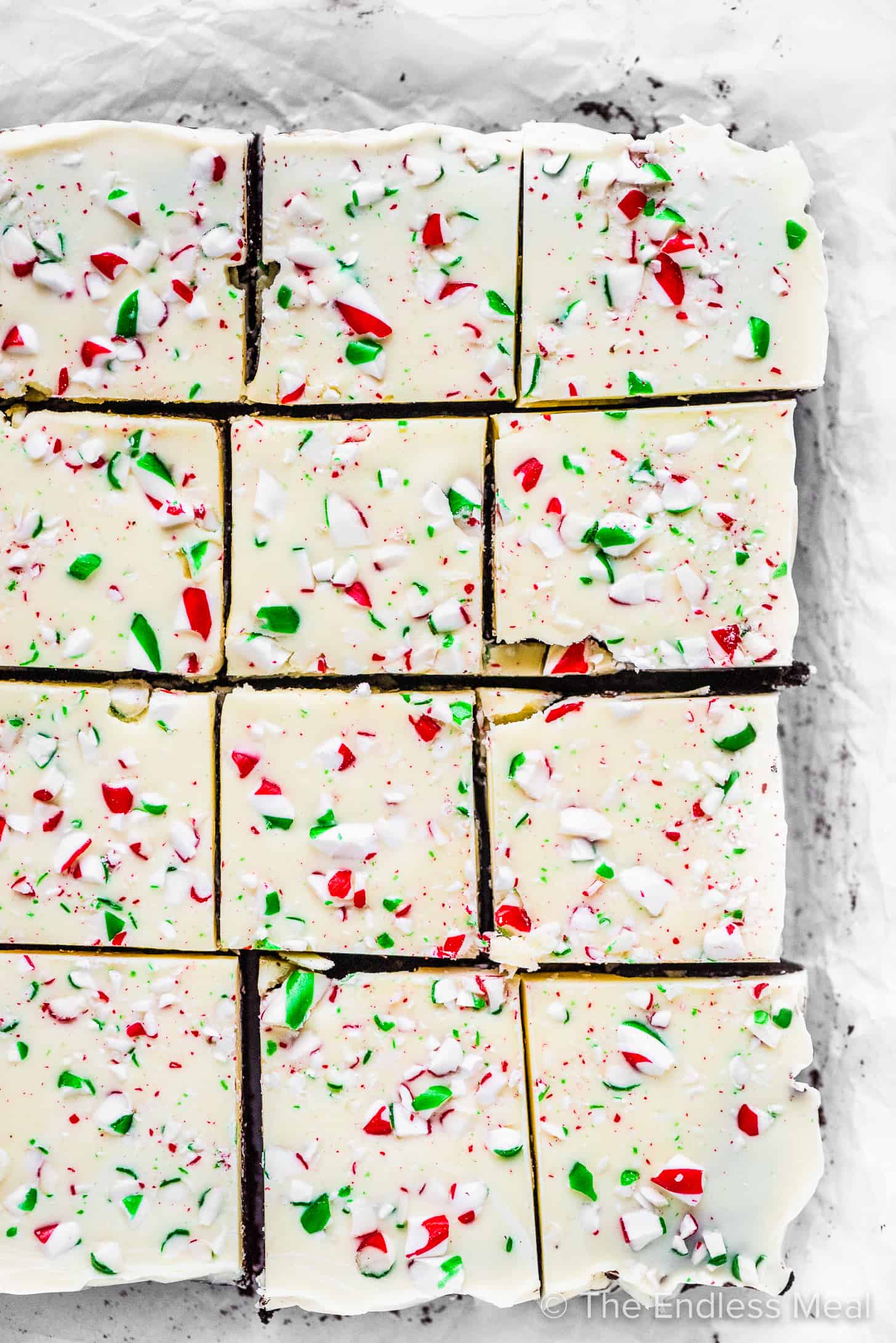 Peppermint bark brownies cut into squares on parchment paper,