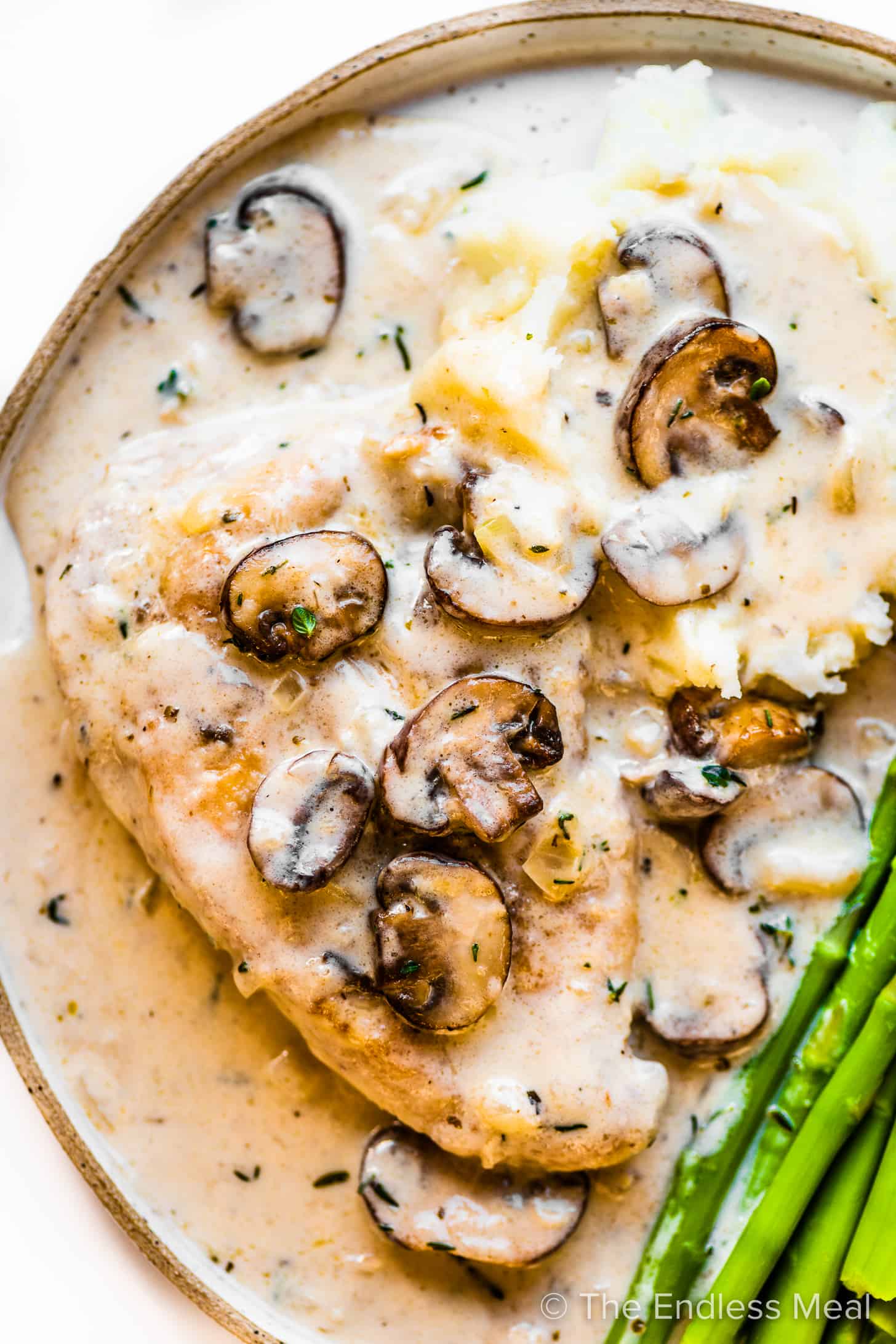 Champagne Chicken on a plate with mashed potatoes and asparagus.