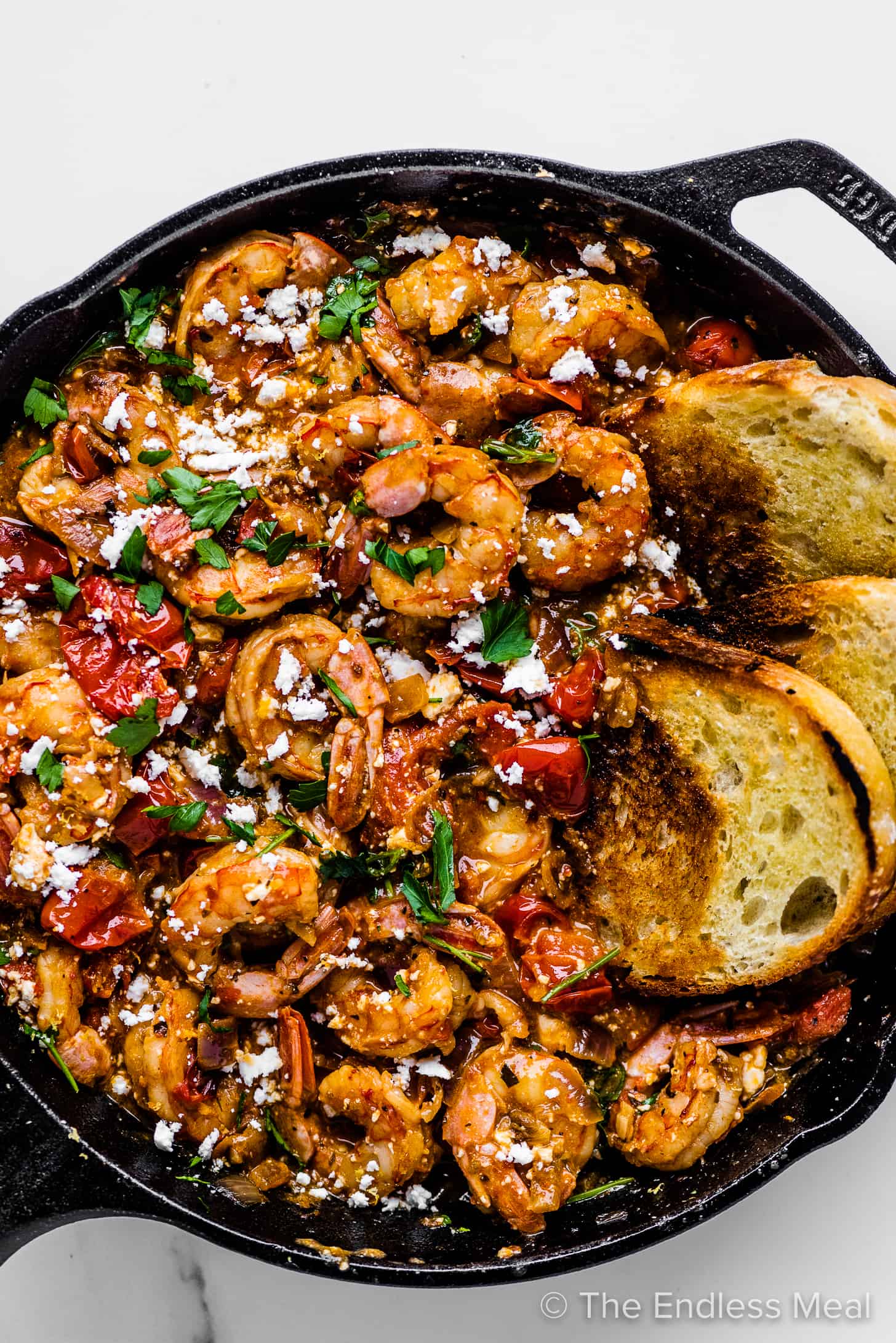 Greek shrimp with feta tomato sauce in a pan with some toasted bread.