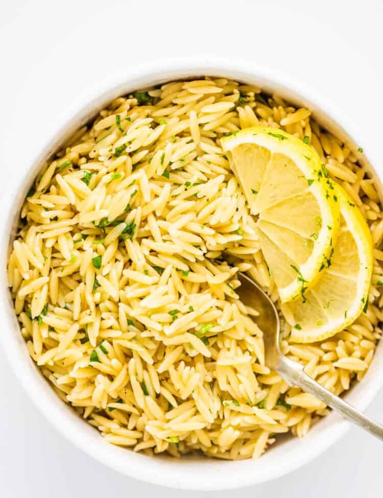 Lemon butter orzo in a white bowl with a serving spoon,