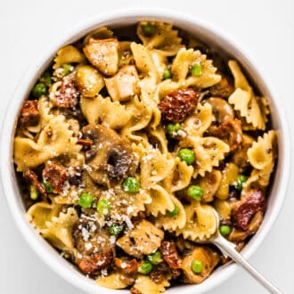 a bowl of Farfalle with Chicken and Roasted Garlic with a fork in it.