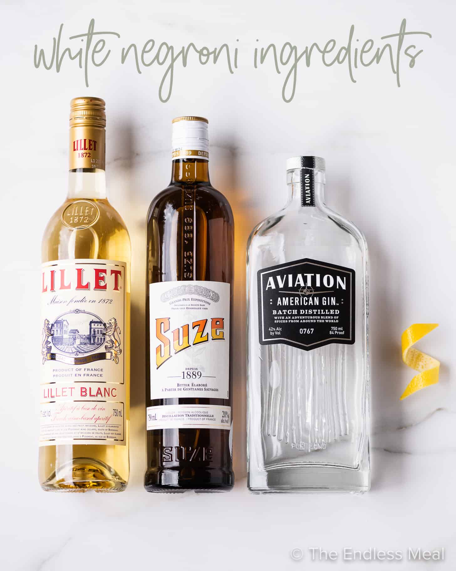 The ingredients to make a white negroni - Lillet, Suze, and gin