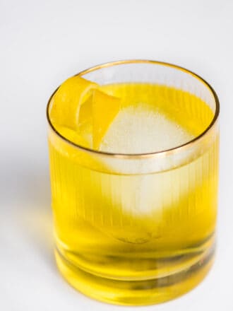 A White Negroni in a glass with a lemon twist