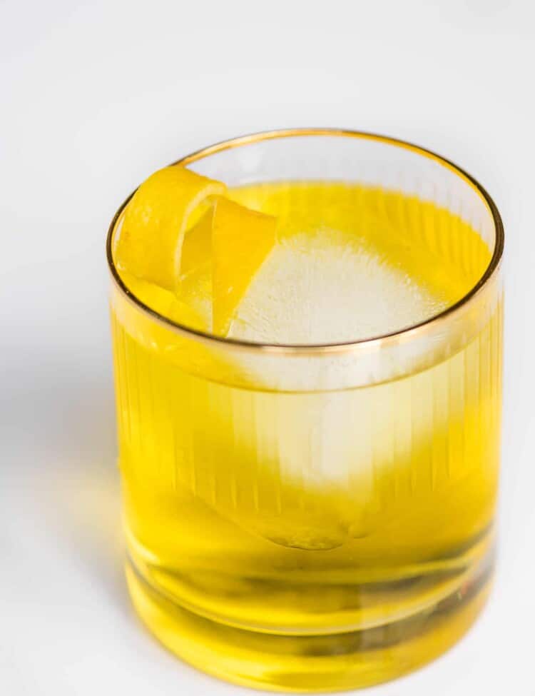 A White Negroni in a glass with a lemon twist