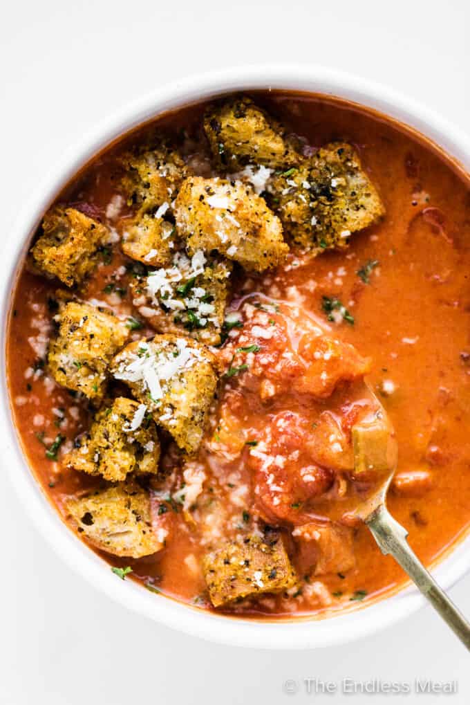 a bowl of chunky tomato bacon soup with croutons.