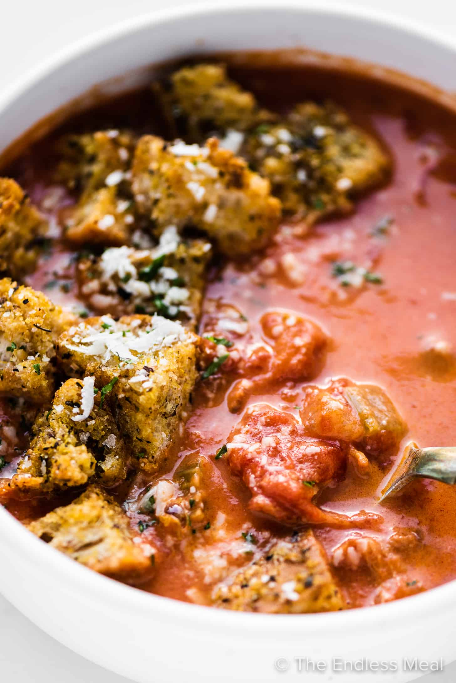 a close up of tomato bacon soup with croutons.