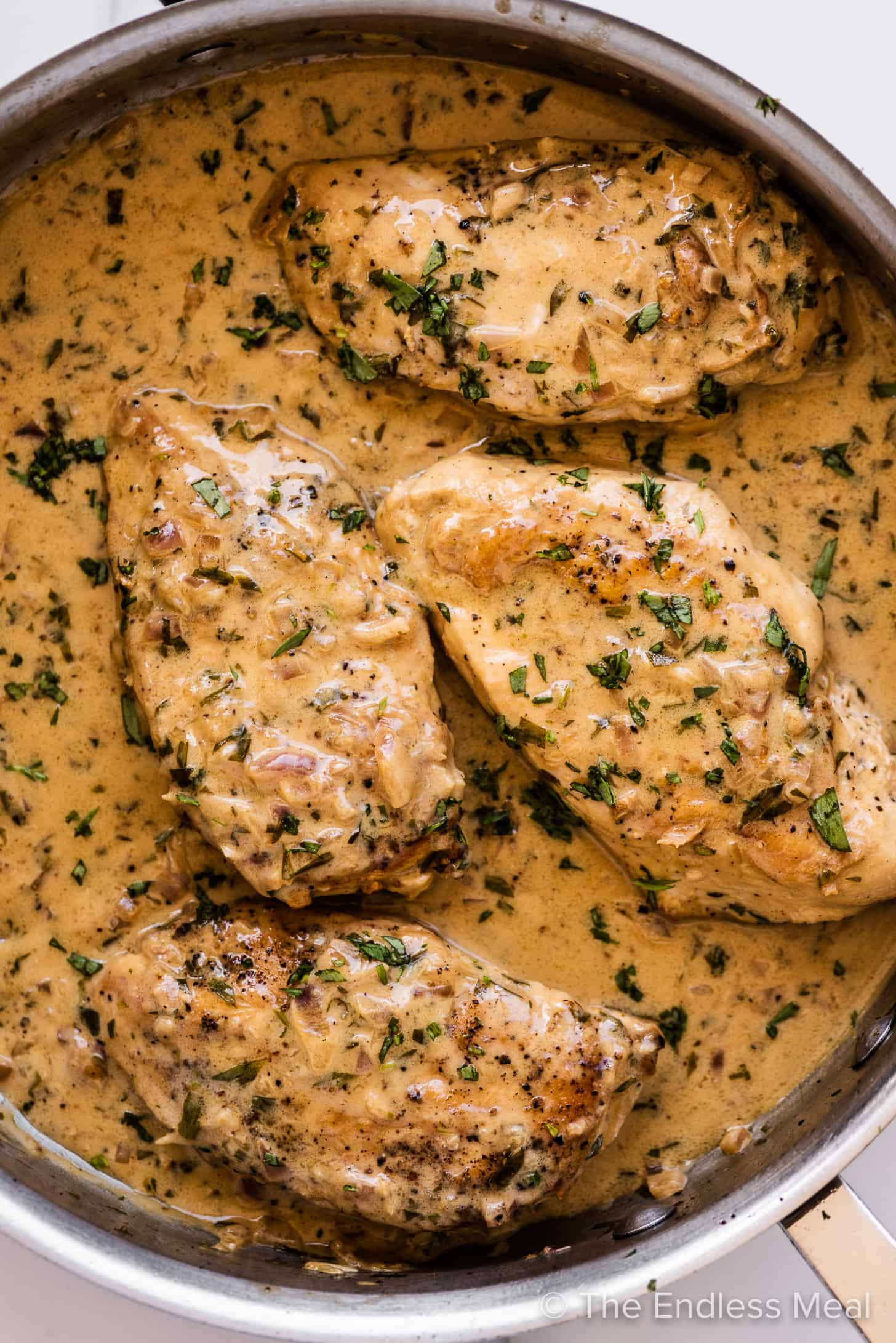 4 pieces of tarragon chicken in a pan with a creamy tarragon sauce.