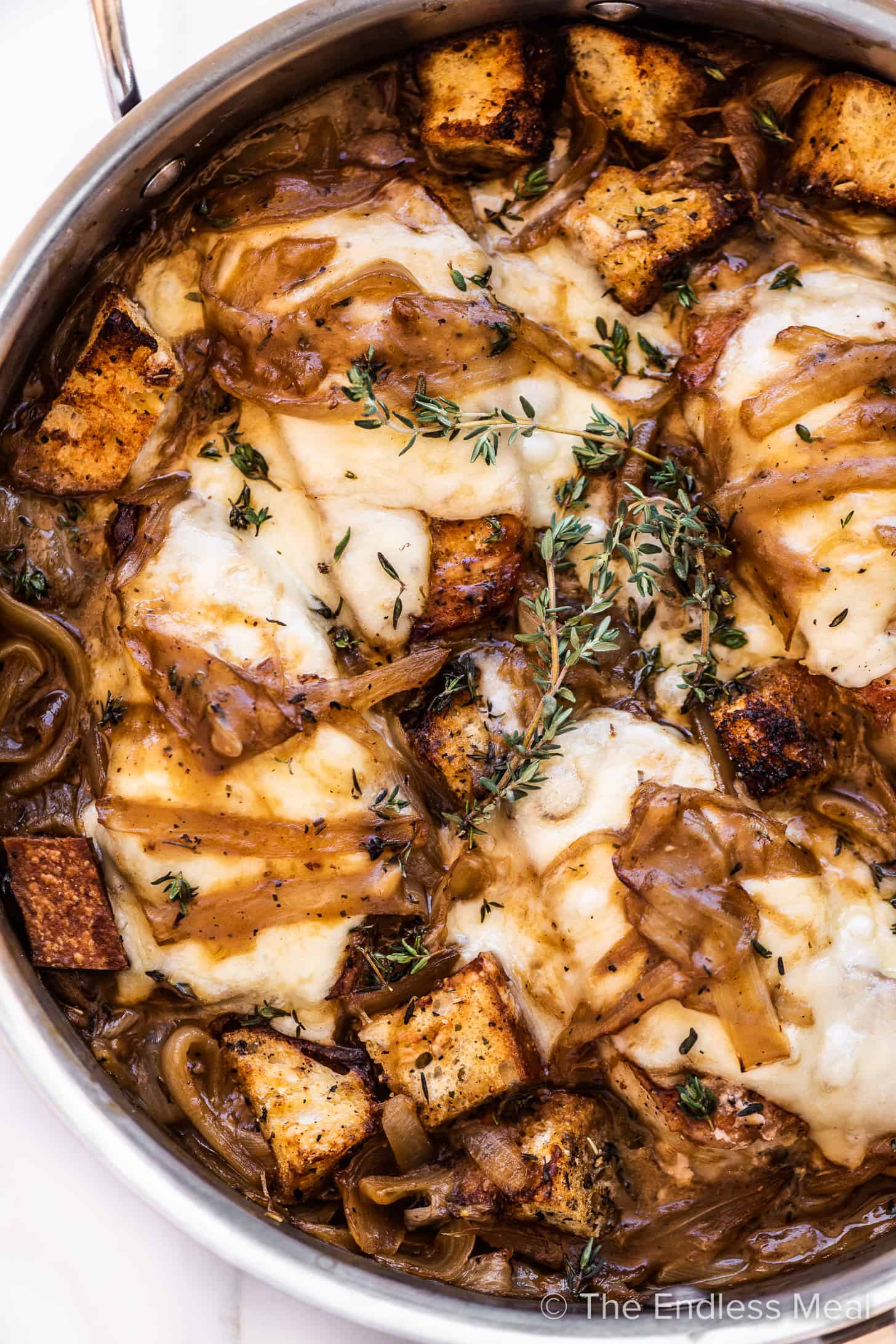 smothered french onion pork chops in a pan with croutons