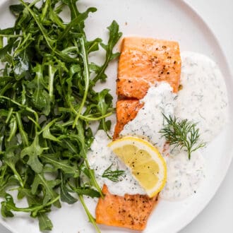 juicy salmon with lemon dill sauce on a plate with salad