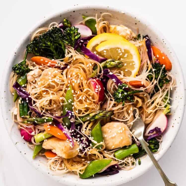 spring vegetable noodle stir fry in a bowl with a fork.