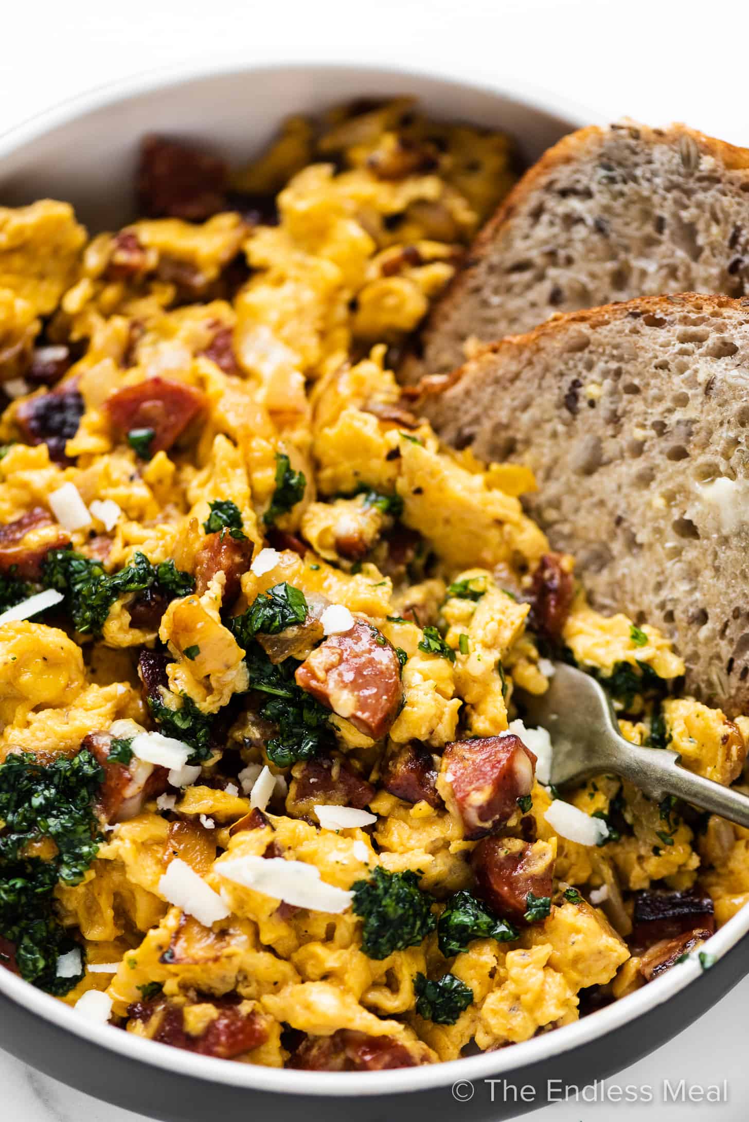 a close up of chorizo scrambled eggs served with toast.