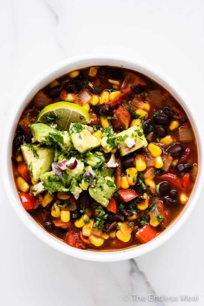 black bean corn chili in a bowl topped with avocado salsa