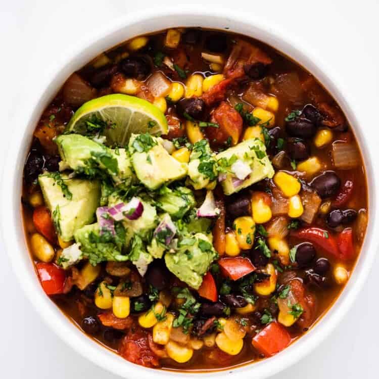 black bean corn chili in a bowl topped with avocado salsa