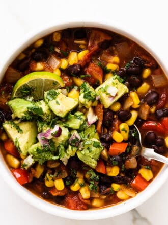a bowl of black bean and corn chili topped with avocado salsa.