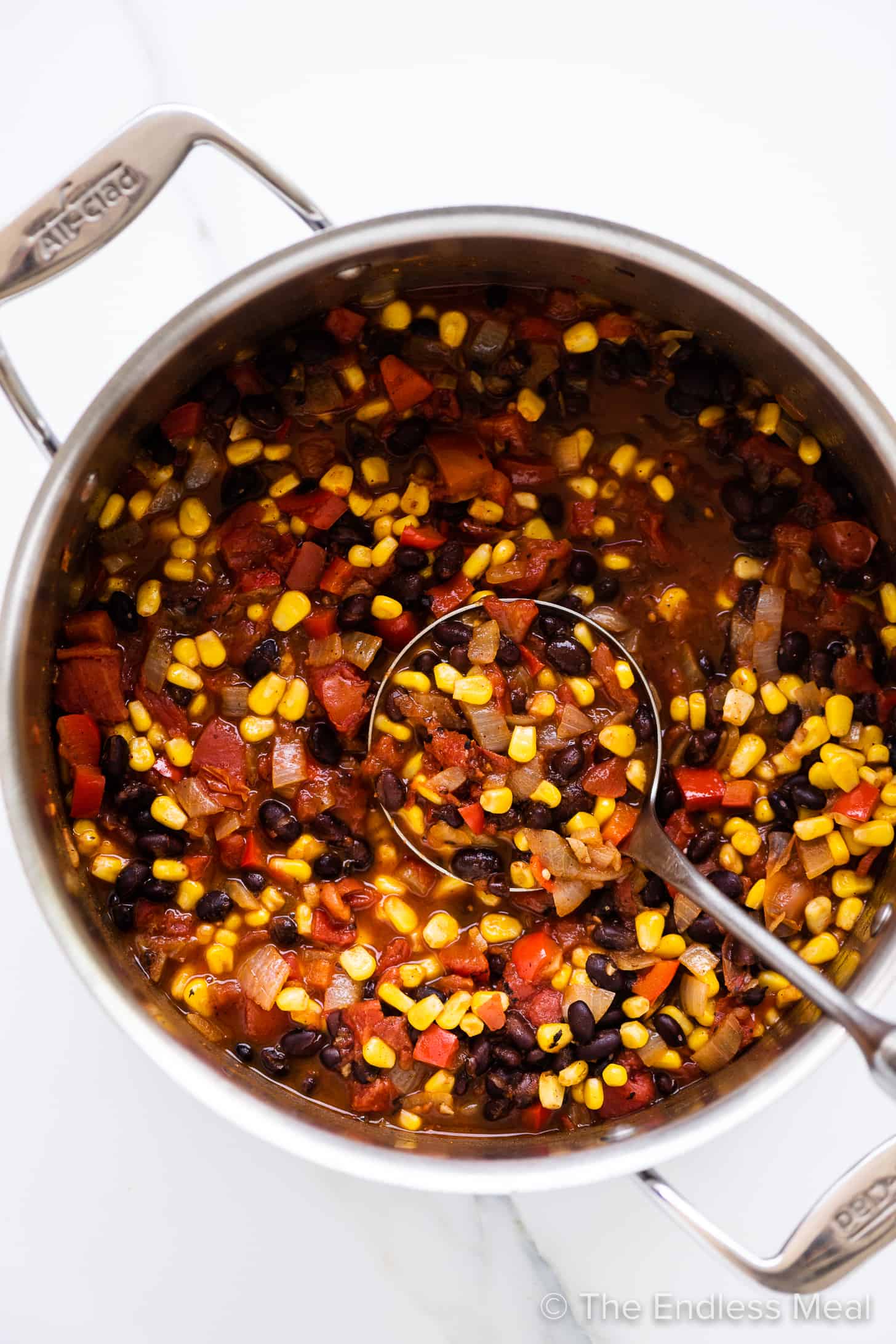 a pot of black bean and corn chili with a ladle in it.