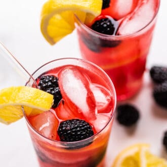 blackberry lemonade in a glass with lemons and blackberries.