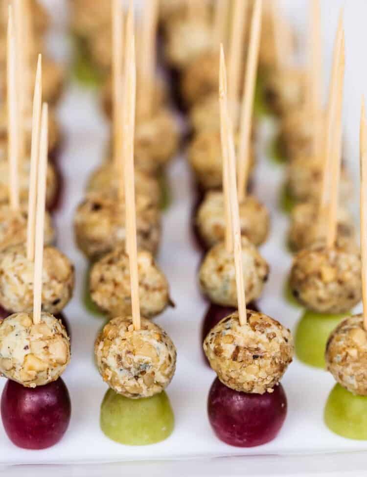 rows of blue cheese and grape appetizer on toothpicks on a plate.