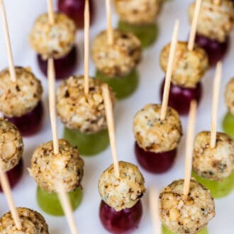 blue cheese grape appetizers on toothpicks lined up on a plate