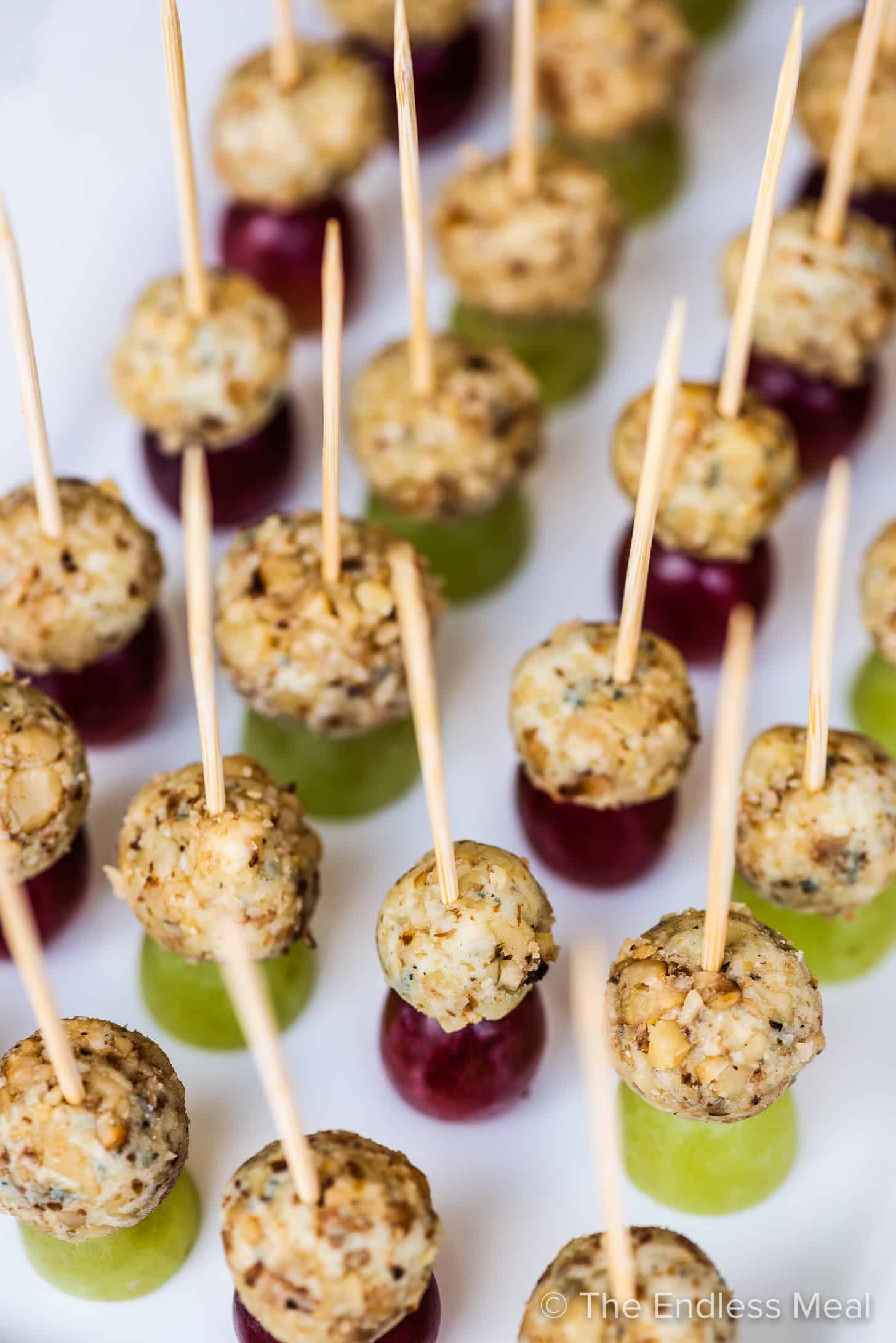 blue cheese grape appetizers on toothpicks lined up on a plate