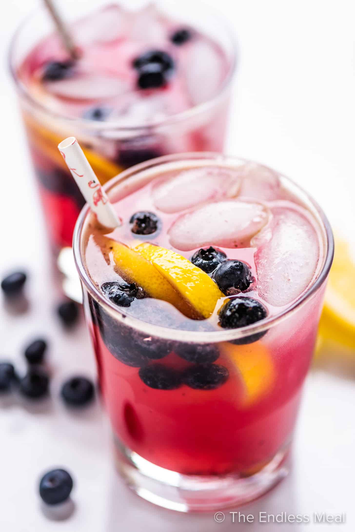 two glasses filled with lemonade with blueberry syrup