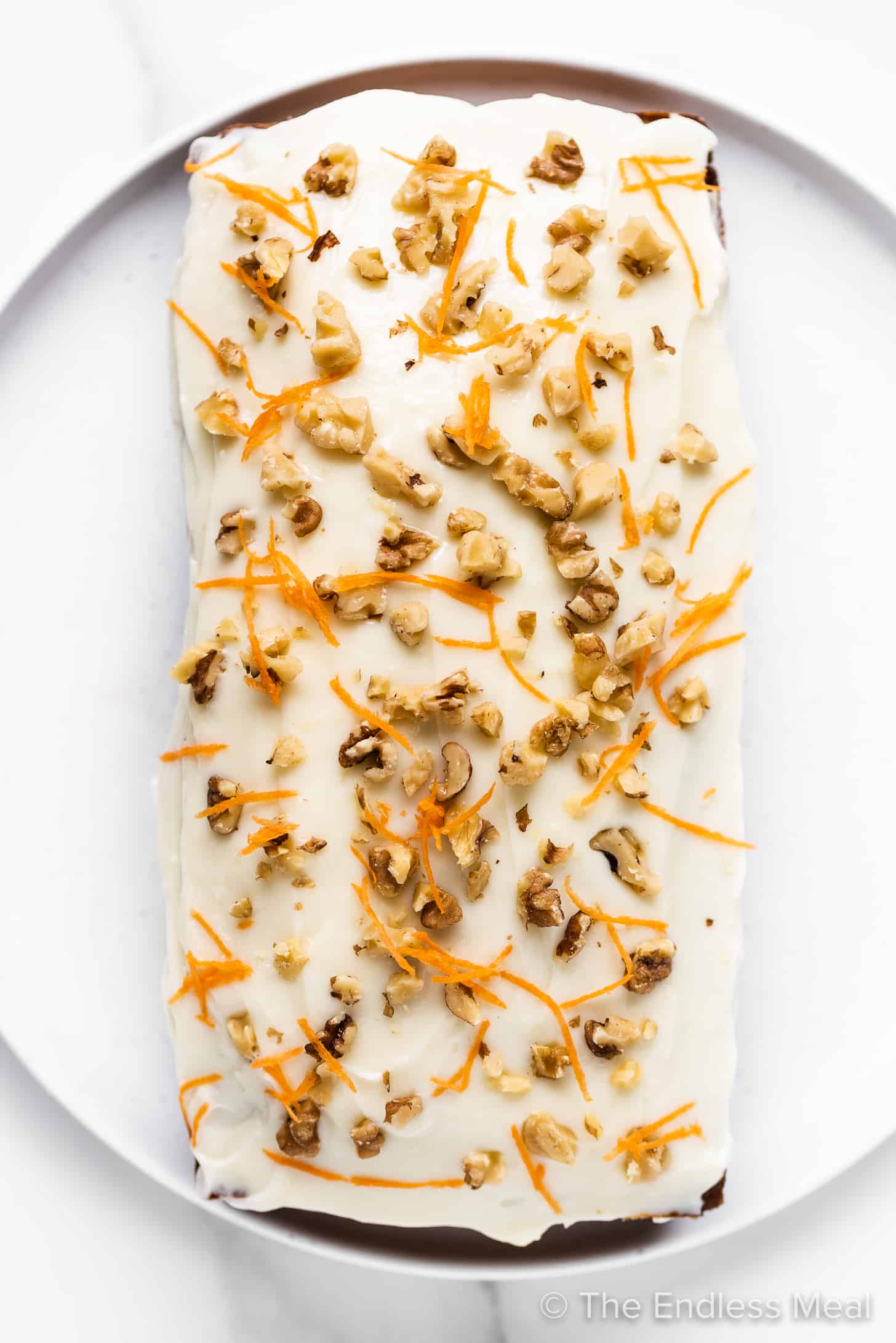 carrot banana bread topped with cream cheese frosting and walnuts