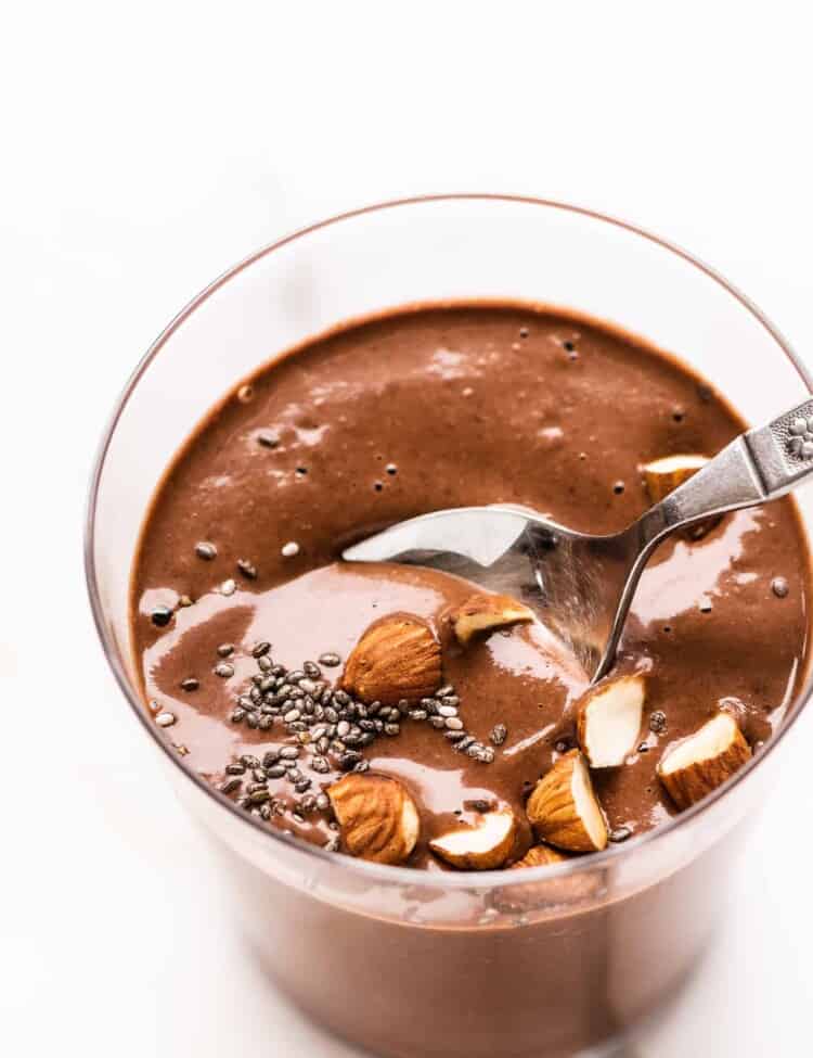 a glass of chocolate almond chia seed smoothie in a glass with a spoon