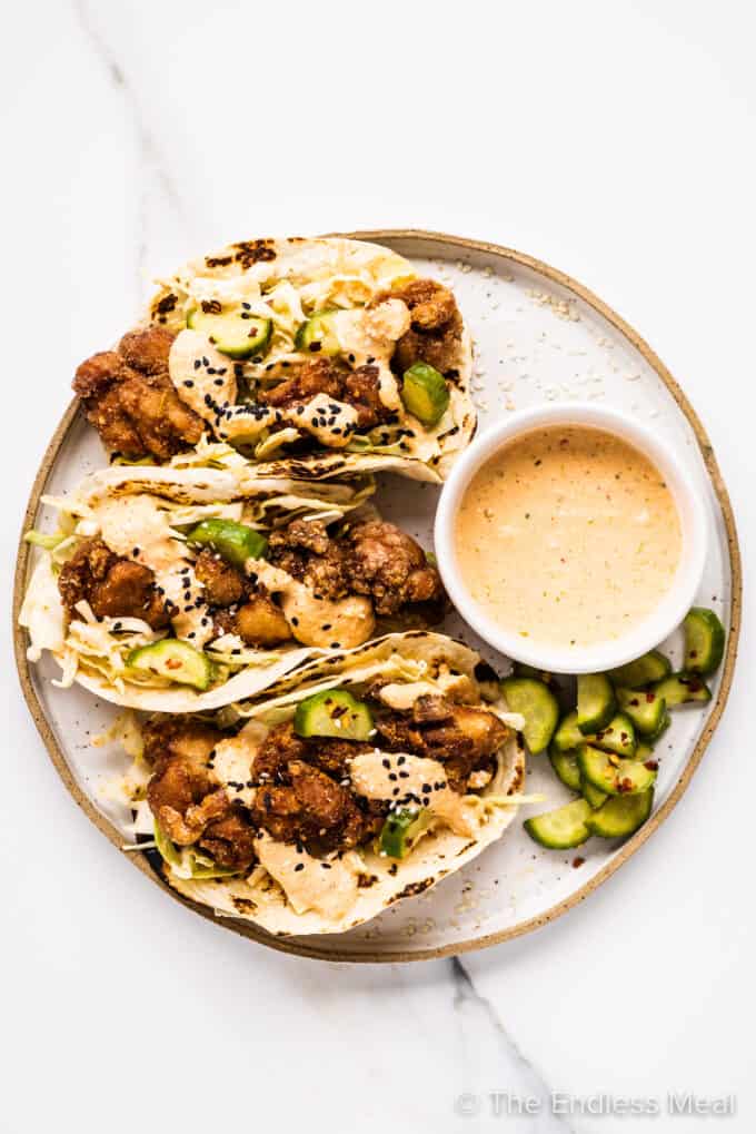 a plate of three chicken karaage tacos with a side of kimchi mayo