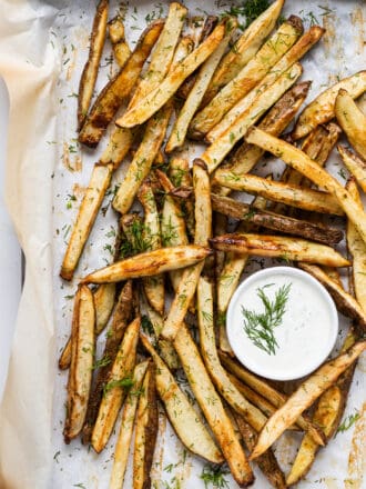 dill french fries on a baking sheet with dill yogurt dip