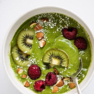 a green smoothie bowl topped with fresh fruit.