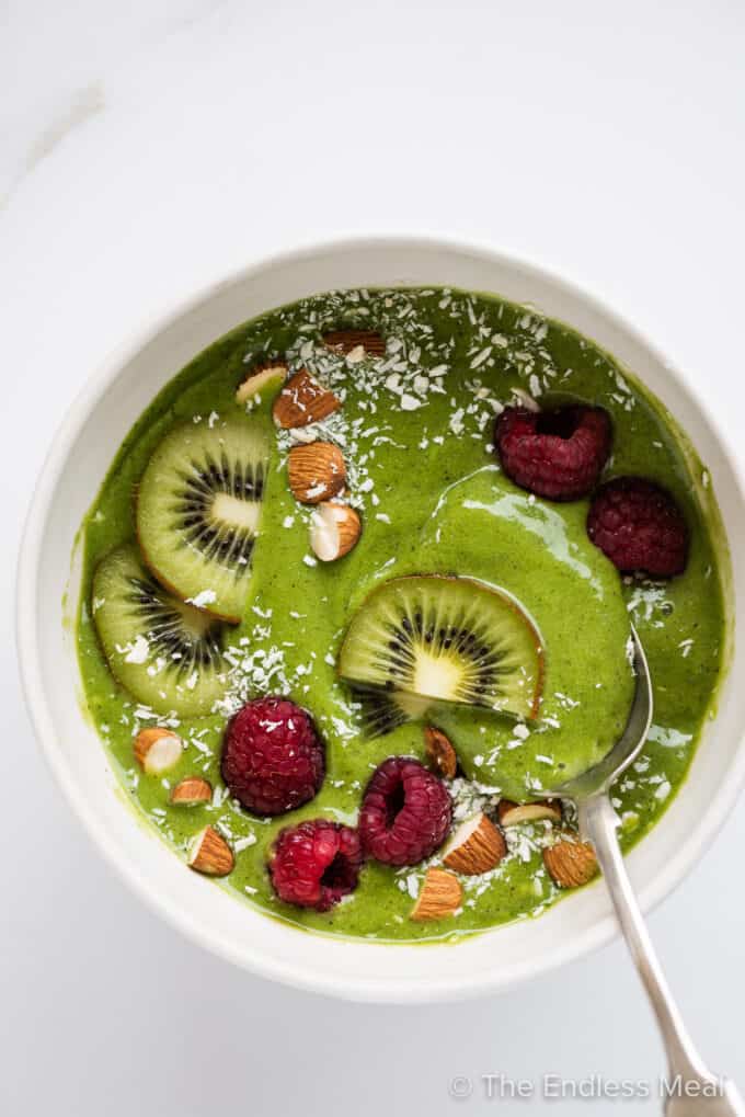a green smoothie bowl topped with fresh fruit.