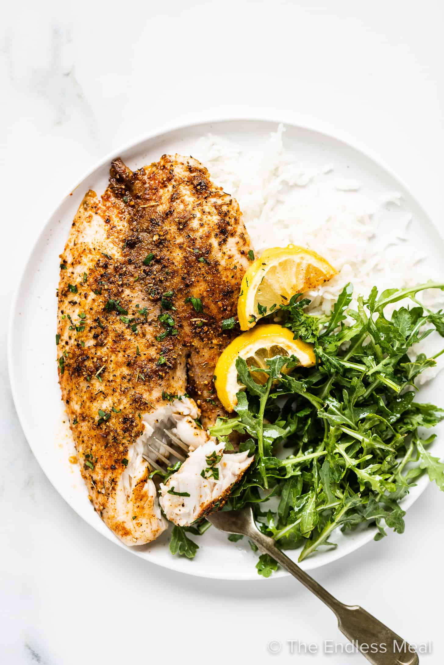 lemon pepper fish on a plate with a salad