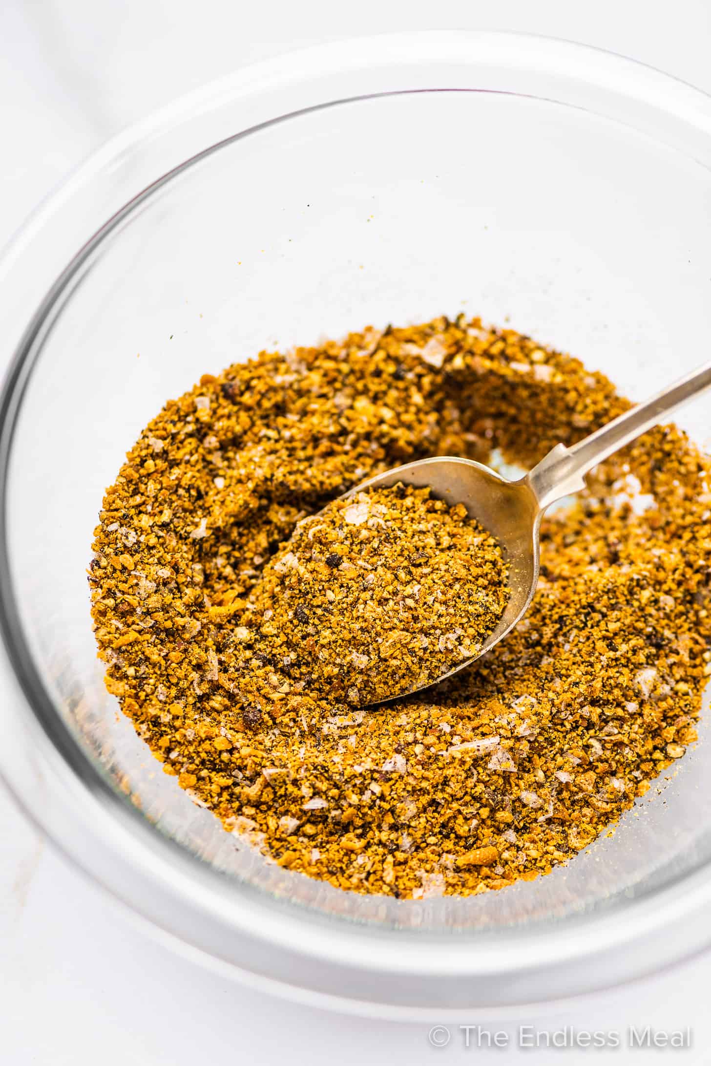 a close up of lemon pepper seasoning being mixed in a glass bowl