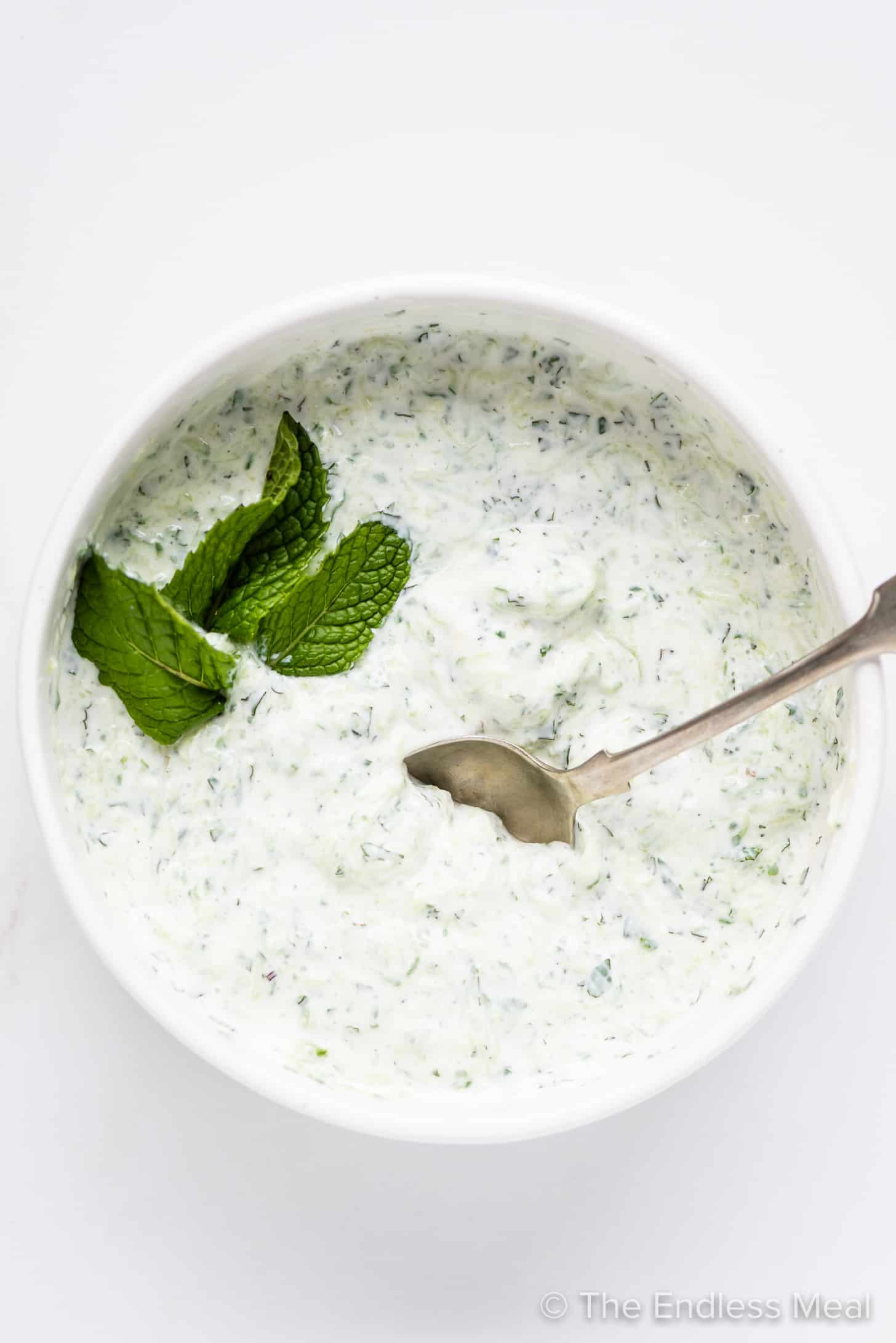 Mint Tzatziki in a serving bowl with a spoon and mint leaves