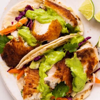 two Baja Fish Tacos on a plate with avocado sauce