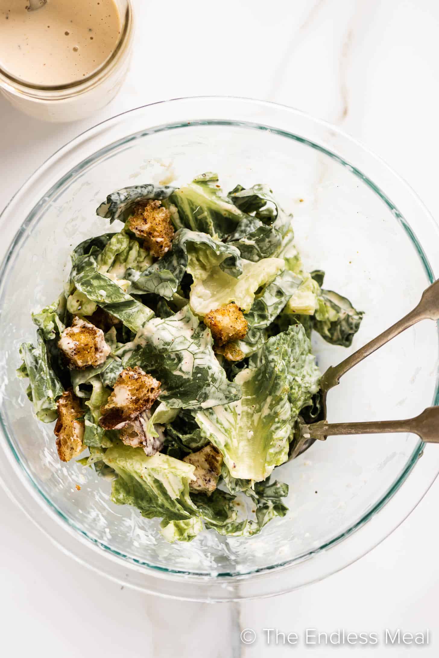 a bowl of caesar salad with a jar of our Easy Caesar Salad Dressing beside it.