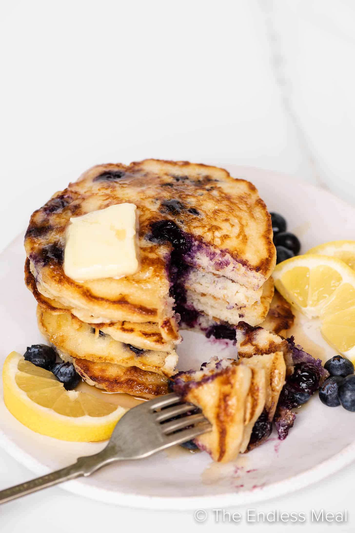 a stack of Lemon Blueberry Pancakes with a bite cut out