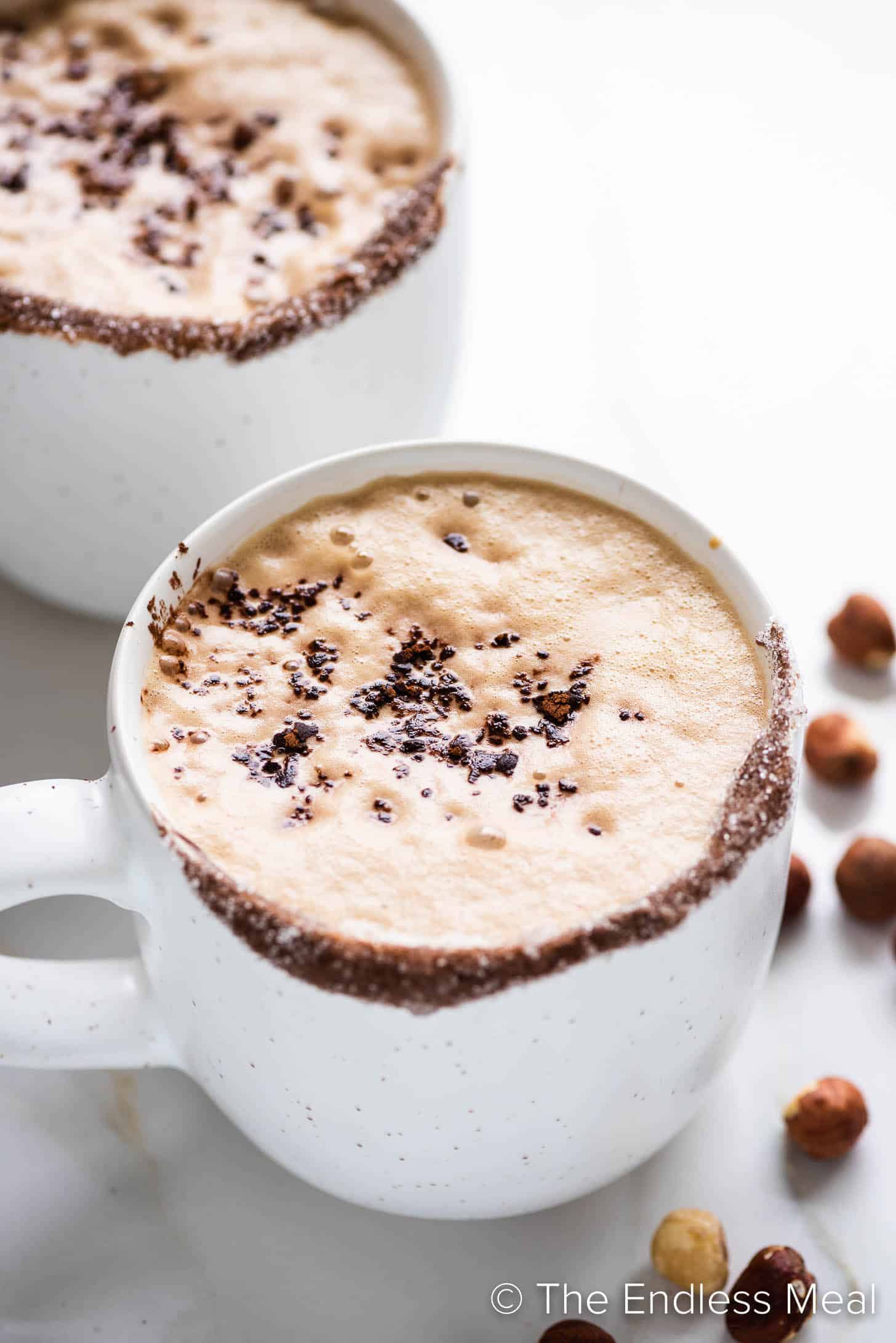 a creamy nutella latte with hazelnuts beside it