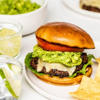 A guacamole burger on a plate with tortilla chips