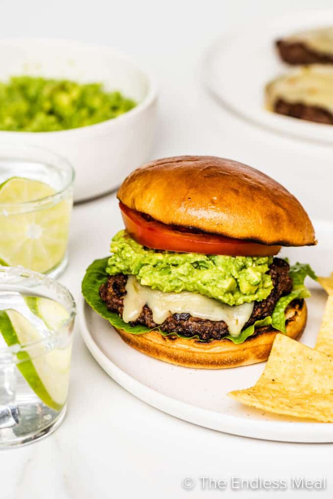 A guacamole burger on a plate with tortilla chips
