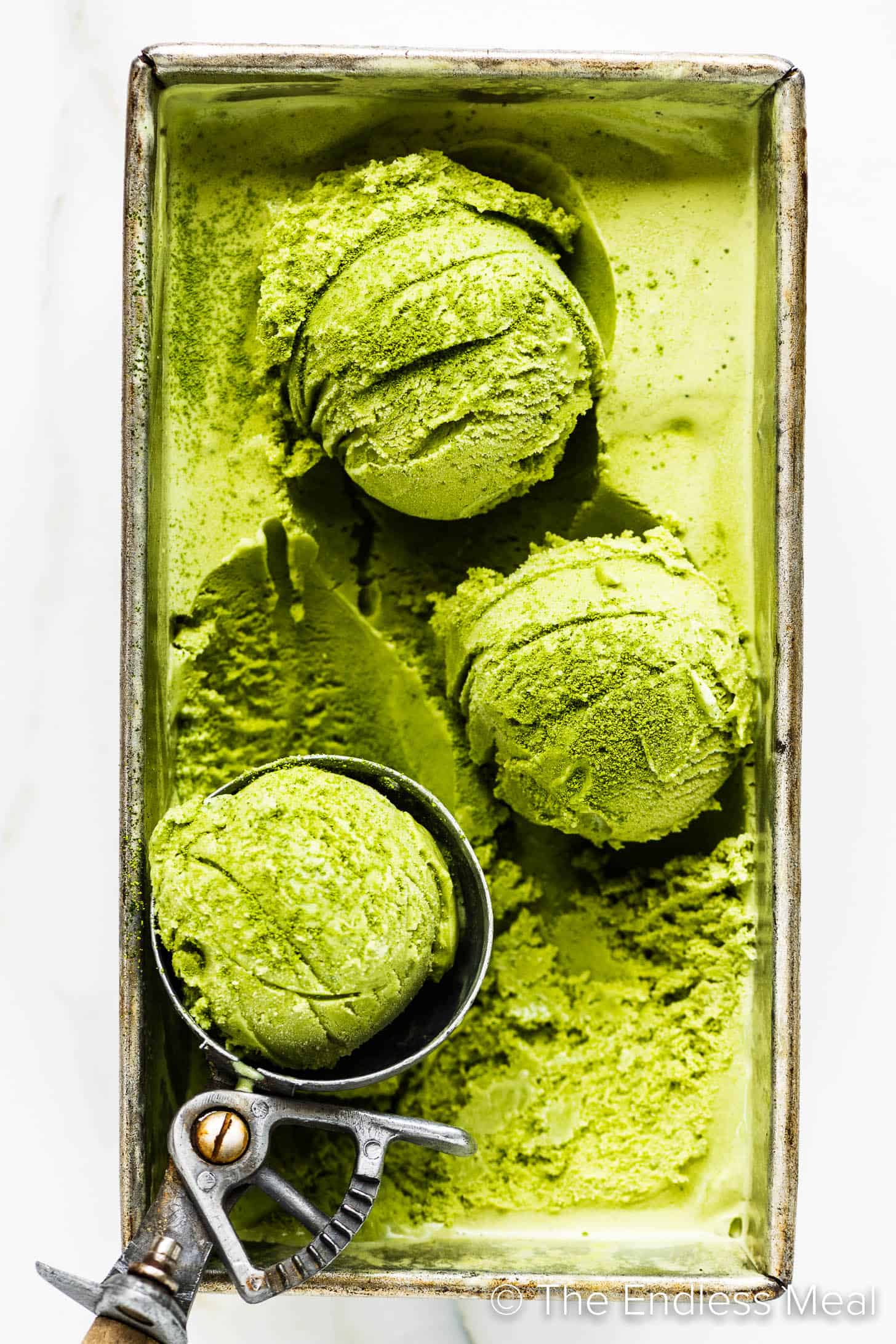 an ice cream scoop making balls of matcha ice cream