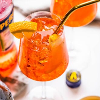 a close up of an aperol spritz in a wine glass