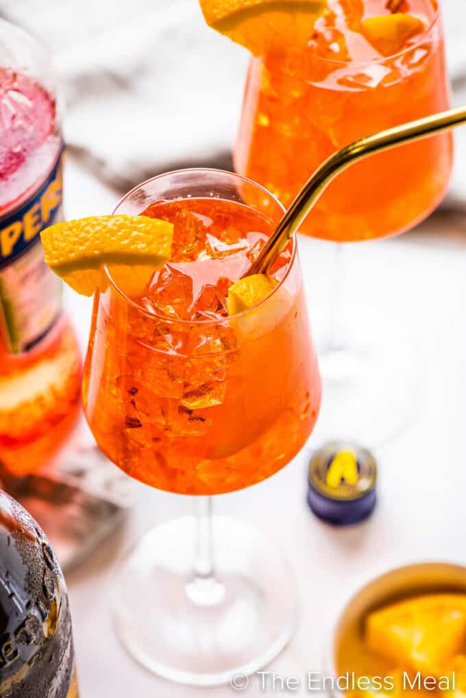 a close up of an aperol spritz in a wine glass