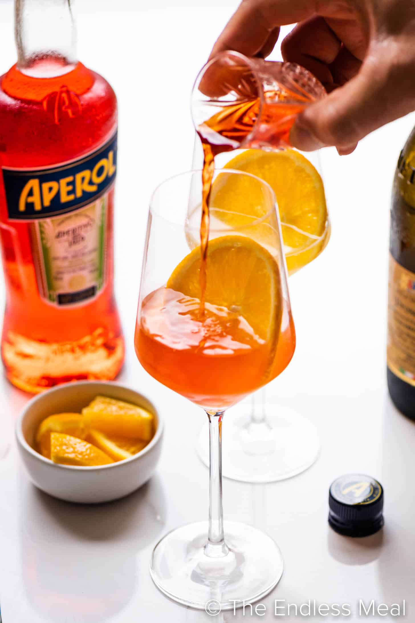 pouring aperol into a wine glass