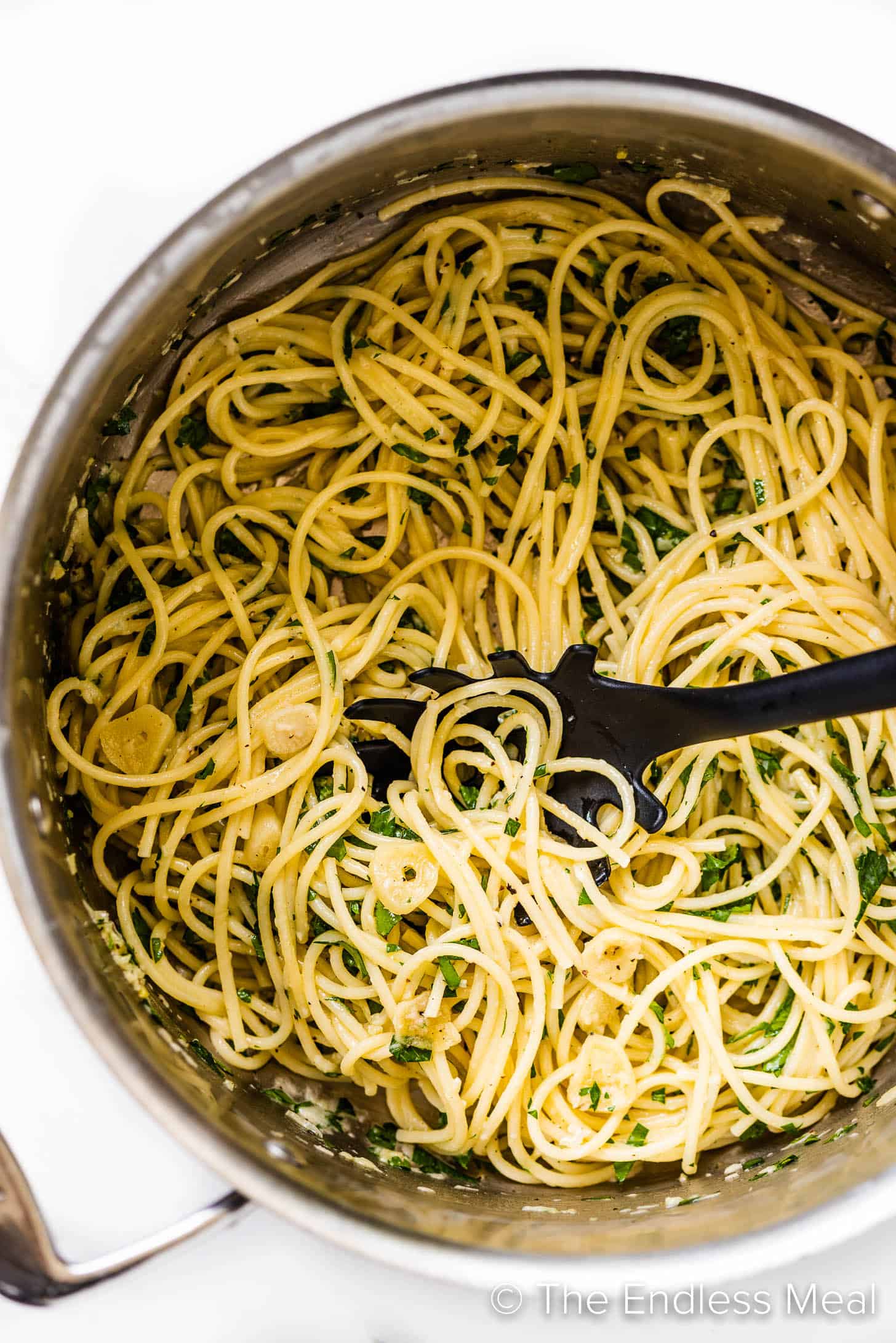 a pasta fork scooping some garlic butter noodles out of a pot