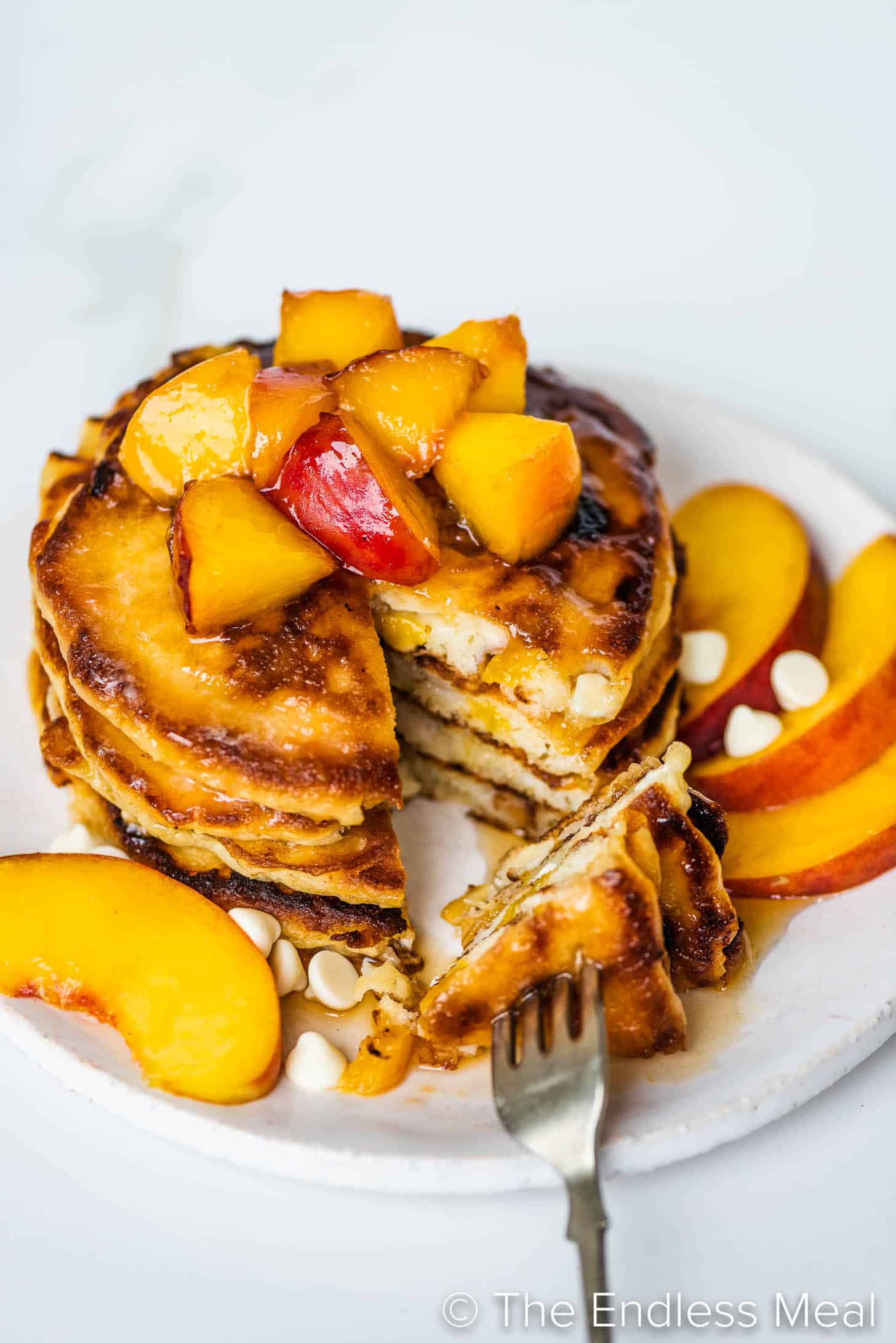 a fork in a stack of peach pancakes
