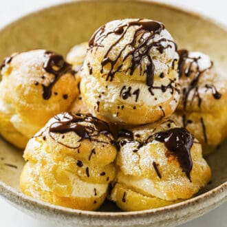 a bowl of Profiteroles drizzled in chocolate